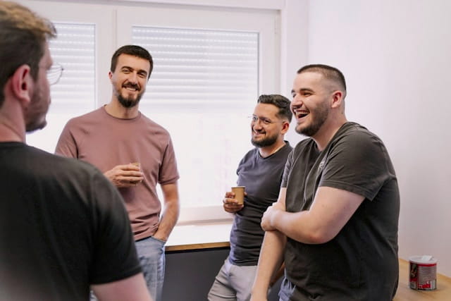 Kube team laughing together during an informal office conversation.