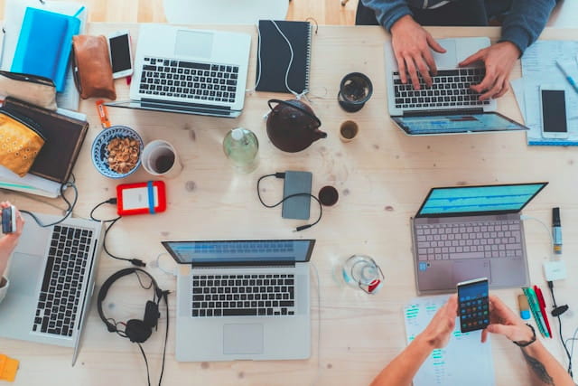 Creative team working together around a desk with laptops, notes and design tools.