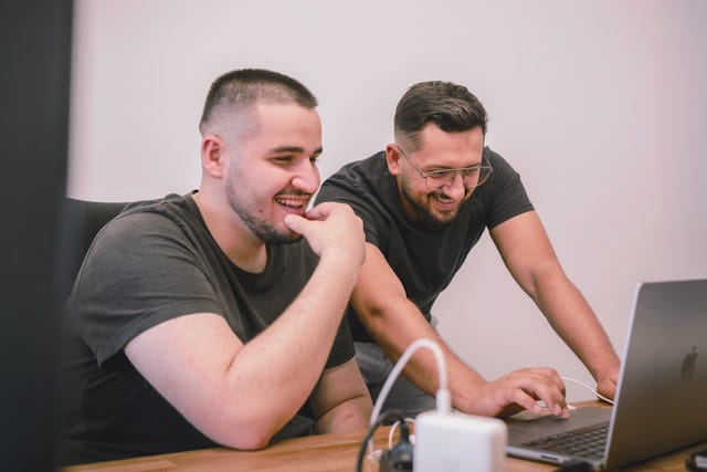 Two designers collaborating and reviewing creative work on a laptop.