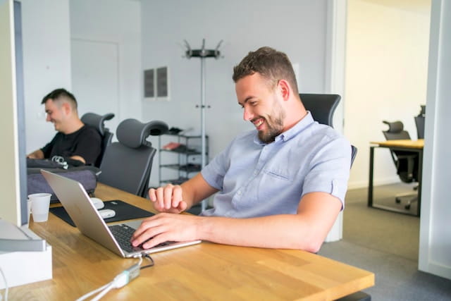 Marketing professional smiling while working on a laptop in the office.