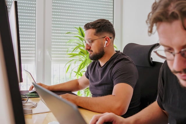 SEO specialist working at a computer beside a colleague in a bright office.