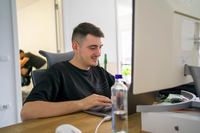 Web designer working at a large desktop monitor in a modern office.